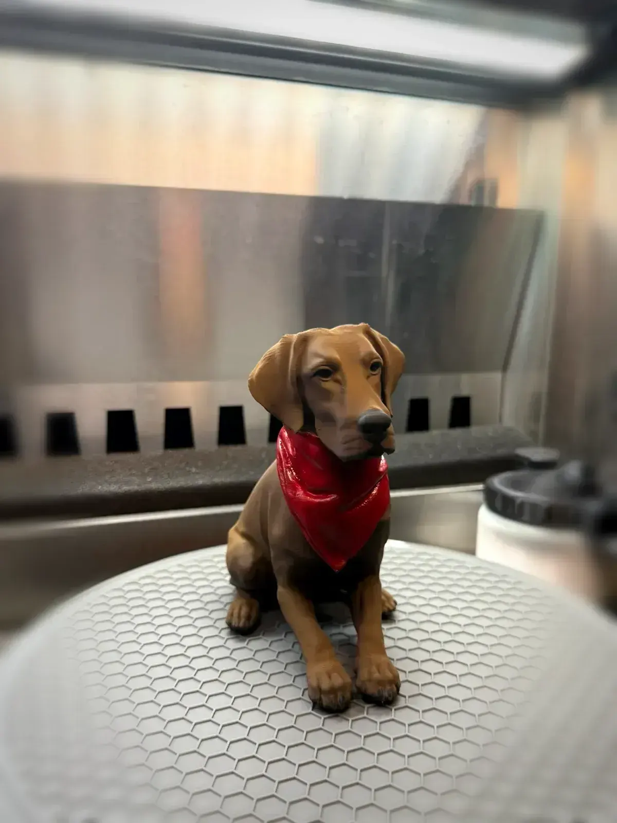 Painted chocolate Labrador sitting and facing forward, wearing a red bandana.